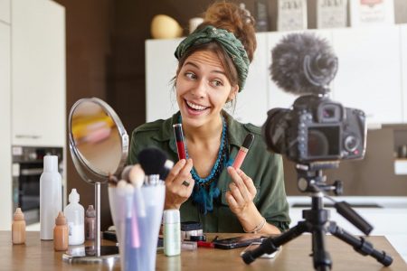 portrait-of-excited-cheerful-young-woman-vlogger-holding-two-lipsticks-of-different-brands-and-compa.jpg